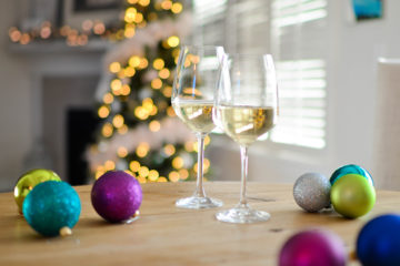 glasses of white wine sitting on a table with holiday ornaments and decor