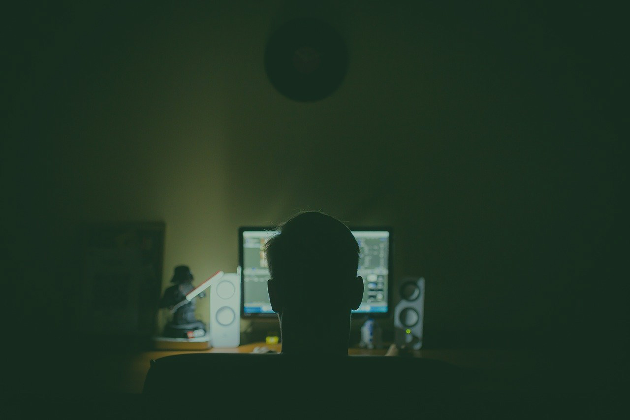 man sitting in the dark on his computer